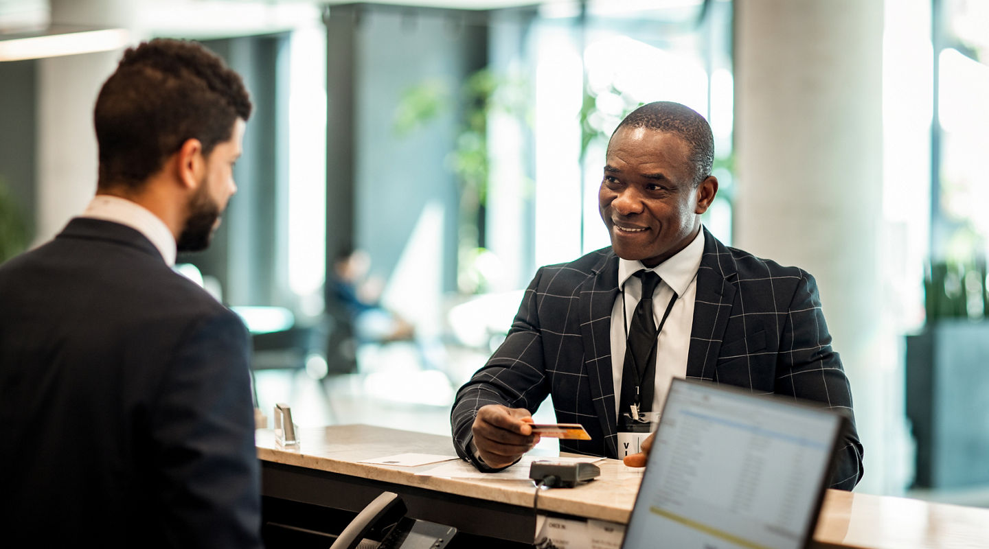 Businessman paying stay at hotel with credit card at reception